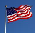 Photo of American flag against a clear, blue sky.