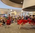 Photo of 5 dancers from NWDT in red and black, flamenco-inspired ballet dresses, spinning in the hearth area while watched by an