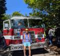 Teen volunteer Nestor, sitting on front of Engine 34 at 2025 Big Truck Day.