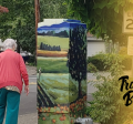 image of a couple walking past a traffic signal box that has been wrapped with art