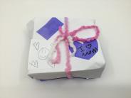 White paper box with purple accents and pink yarn bow that says "I <3 Mom"