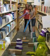 Teens playing mini golf in the library stacks