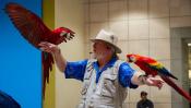 The Oregon Bird Man holding a parrot on each arm