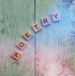 Photo of the word "POETRY" written using Scrabble tiles, on a pastel, rainbow colored, wood grain background.