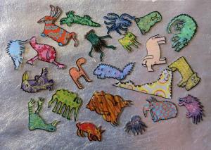 Photo of several brightly colored flat shrinky animals/creatures on a metallic silver background