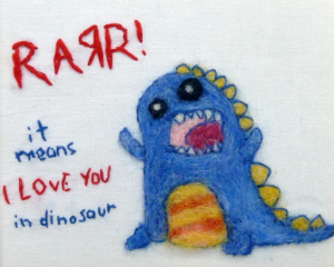 Photo of cartoonish dinosaur in blue, yellow, and red, needle-felted on a white background with the text "RARR! it means I LOVE 