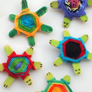 Photo of 5 turtles made from crossed popsicle sticks wrapped with yarn.