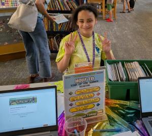 Teen sitting at the summer reading sign up table