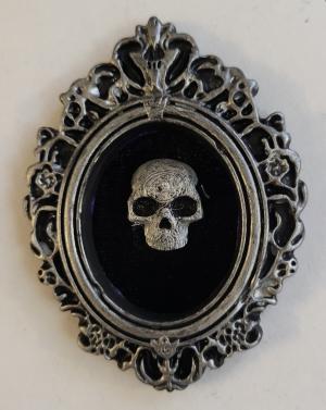 Black and silver skull on black background with silver frame.