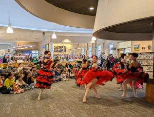 Photo of 5 dancers from NWDT in red and black, flamenco-inspired ballet dresses, spinning in the hearth area while watched by an