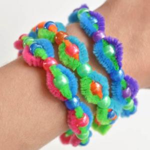 Photo of 3 bracelets on an arm, made from multiple colors of pipe cleaner and pony beads.