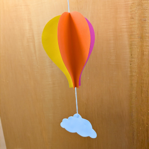 Photo of hot air balloon and cloud shapes, made from paper.
