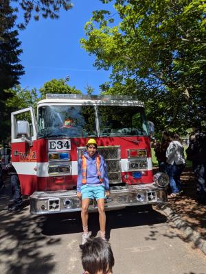 Teen volunteer Nestor, sitting on front of Engine 34 at 2025 Big Truck Day.